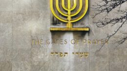 a man walking past a building with a large menorah on it