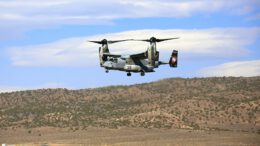 a large military helicopter flying over a field