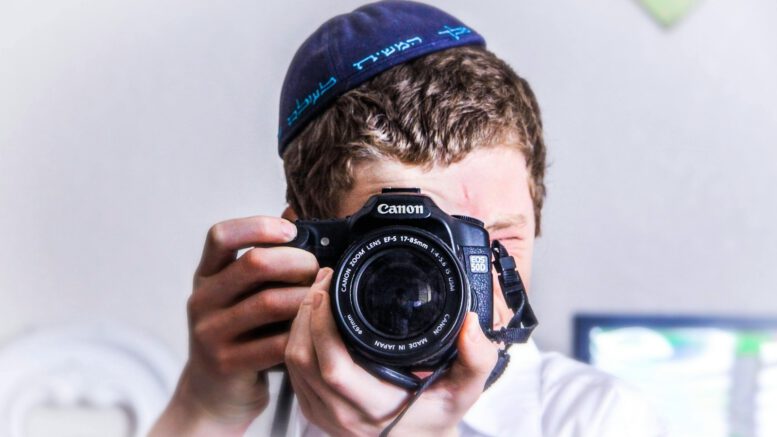 man in blue knit cap holding black and silver nikon dslr camera