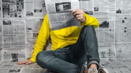 a man sitting on the floor reading a newspaper