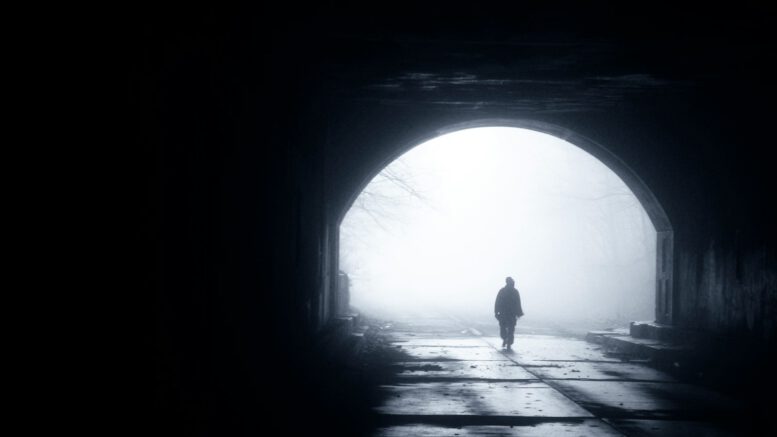 silhouette of person walking out from tunnel during daytime