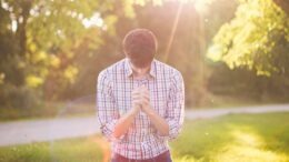 photo of man kneeling on grass near tree